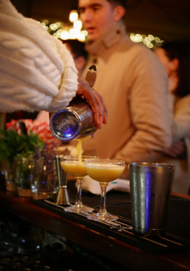 Bartender pouring a cocktail into a martini glass