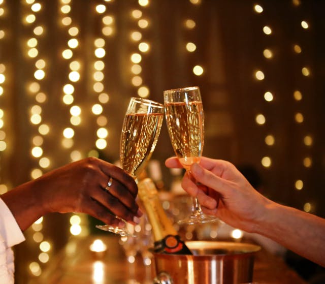 Cheers with champagne flutes and blurred fairy lights